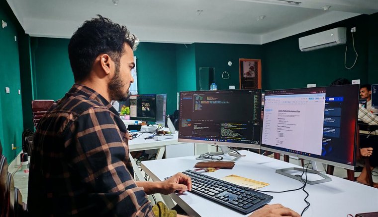توسعهدهنده در حال کدنویسی روی چند نمایشگر در یک فضای کاری حرفهای